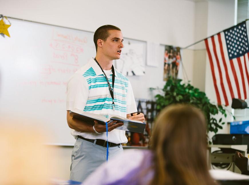 High school teacher standing and talking in front of the class.